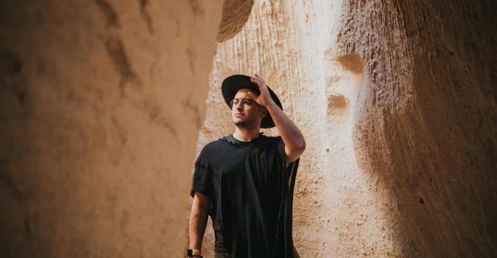 A man wearing a hat standing in a narrow canyon.