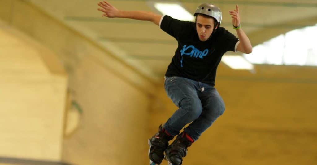 A man jumping while wearing inline skates and a helmet.