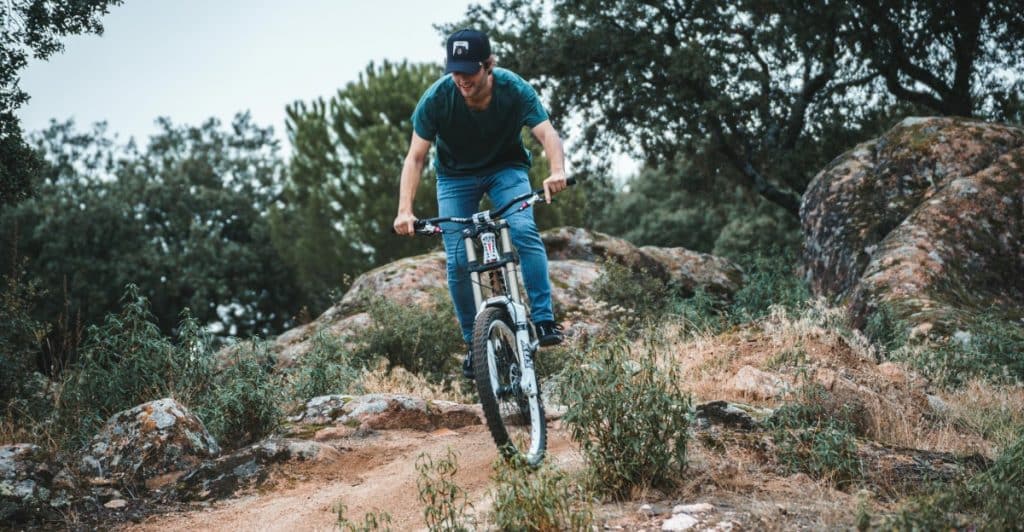 A man riding a mountain bike on a dirt trail through a wooded area.
