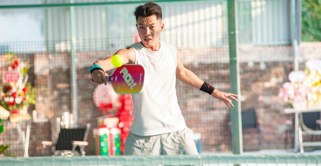 A man is actively playing pickleball on an outdoor court.