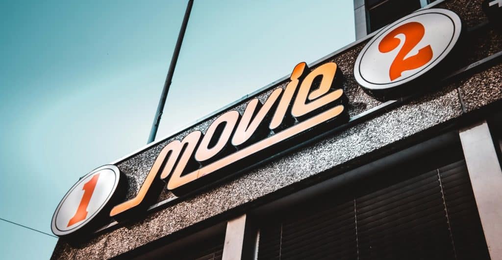 A close-up of a vintage-style movie theater sign with "Movie" written in stylized letters and numbered circles.