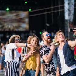 A group of young people taking a selfie at an outdoor festival.