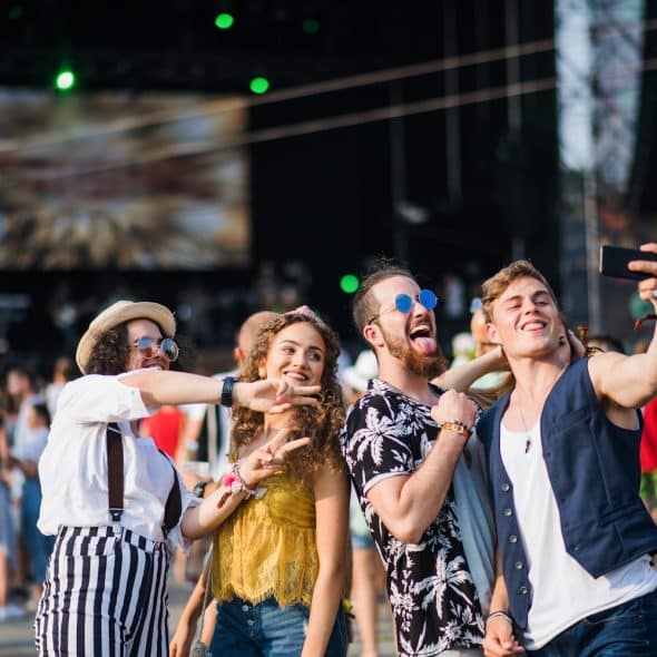A group of young people taking a selfie at an outdoor festival.
