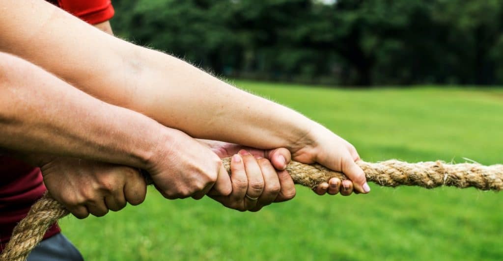 Two people's hands grip a rope in a close-up of a tug-of-war.