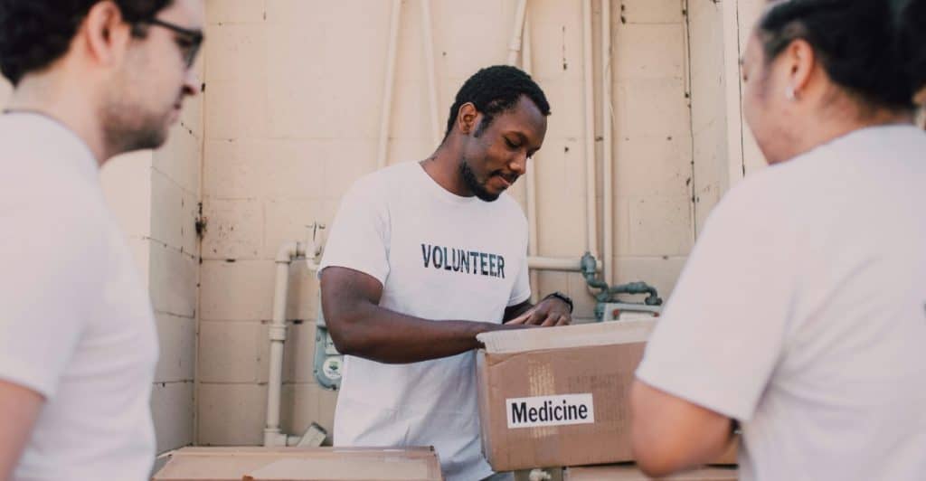 Several people wearing Volunteer shirts are sorting boxes labeled "Food" and "Medicine".