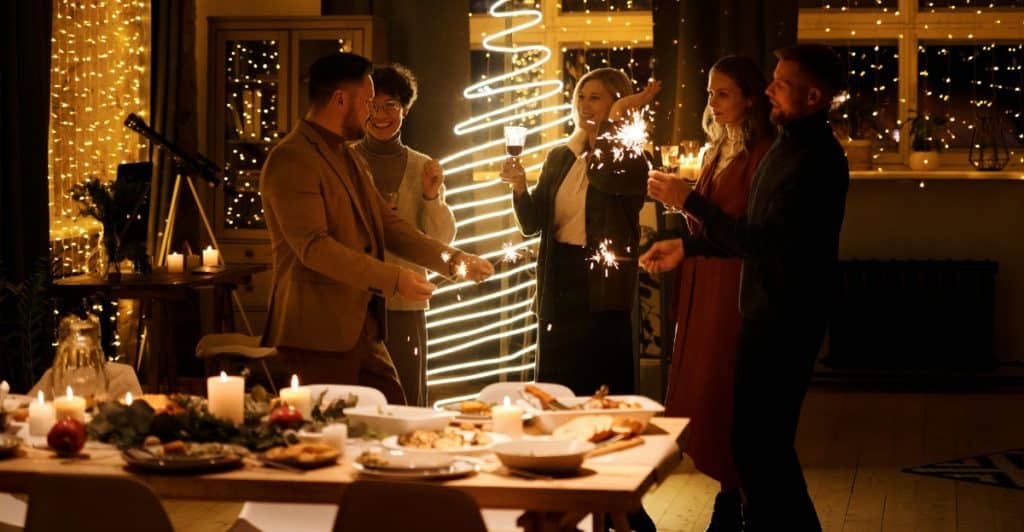 A group of people holding sparklers around a decorated dinner table.