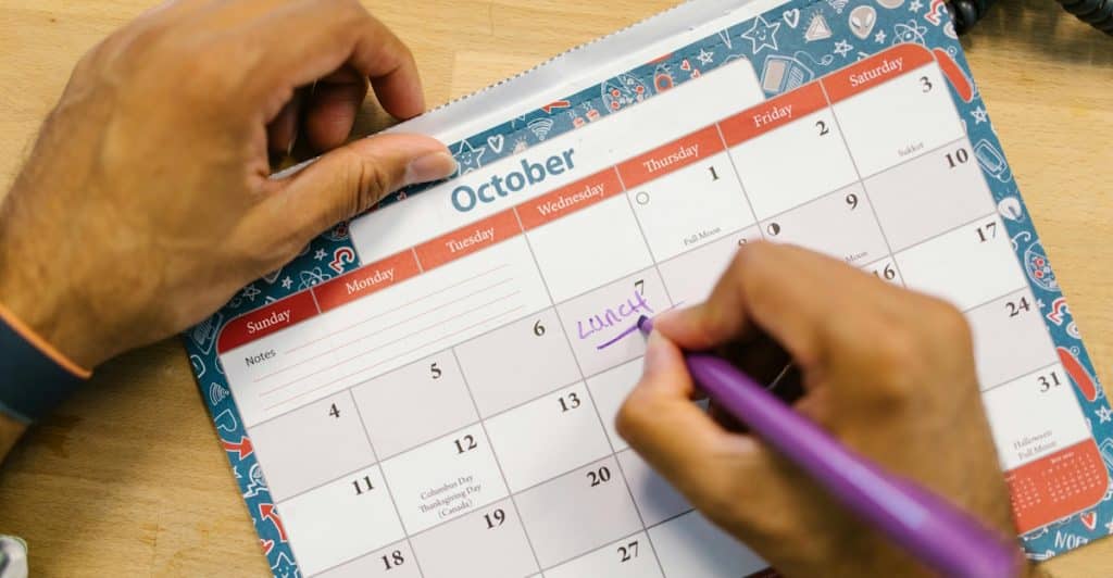 Close-up of hands marking "Lunch" on a calendar.