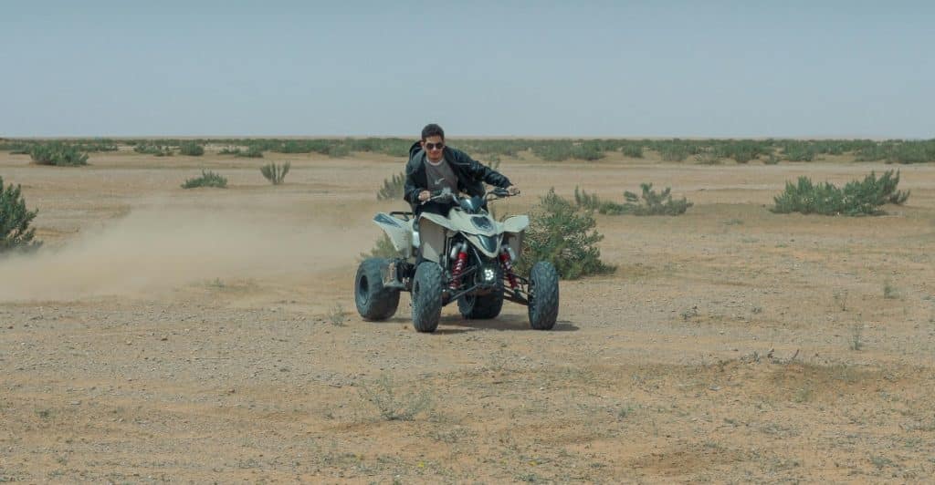 A person riding an ATV across a desert landscape.