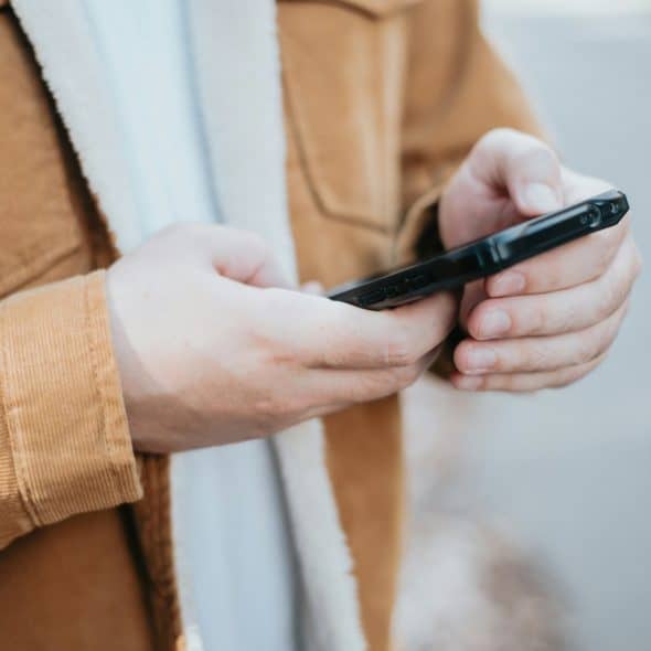 A close-up shot of a person's hands holding a dark-colored smartphone.