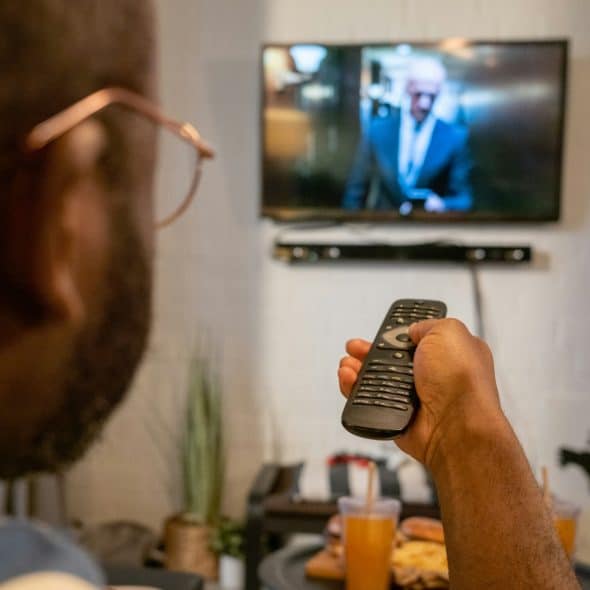 A person pointing a remote towards a TV.