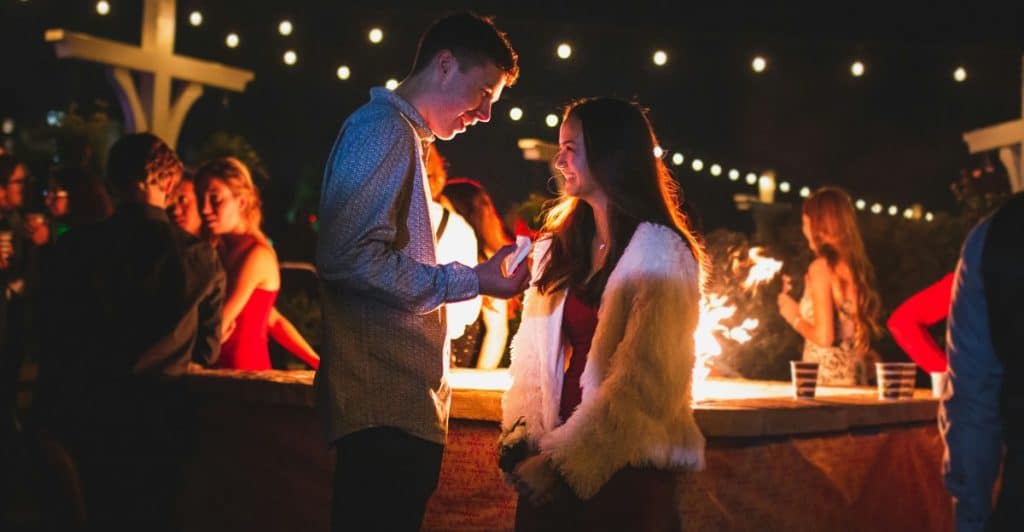 A couple standing close together at an outdoor event at night.