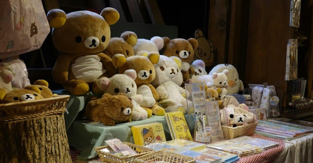 A collection of Rilakkuma plush toys and merchandise displayed on a table with a rustic wooden background.