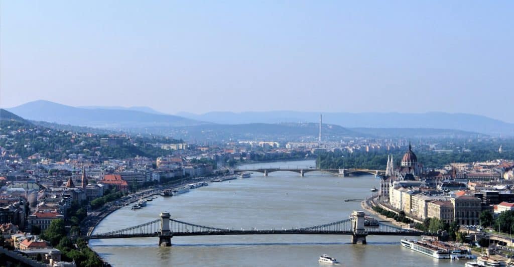 Aerial view of a cityscape with a river running through the center, surrounded by buildings.