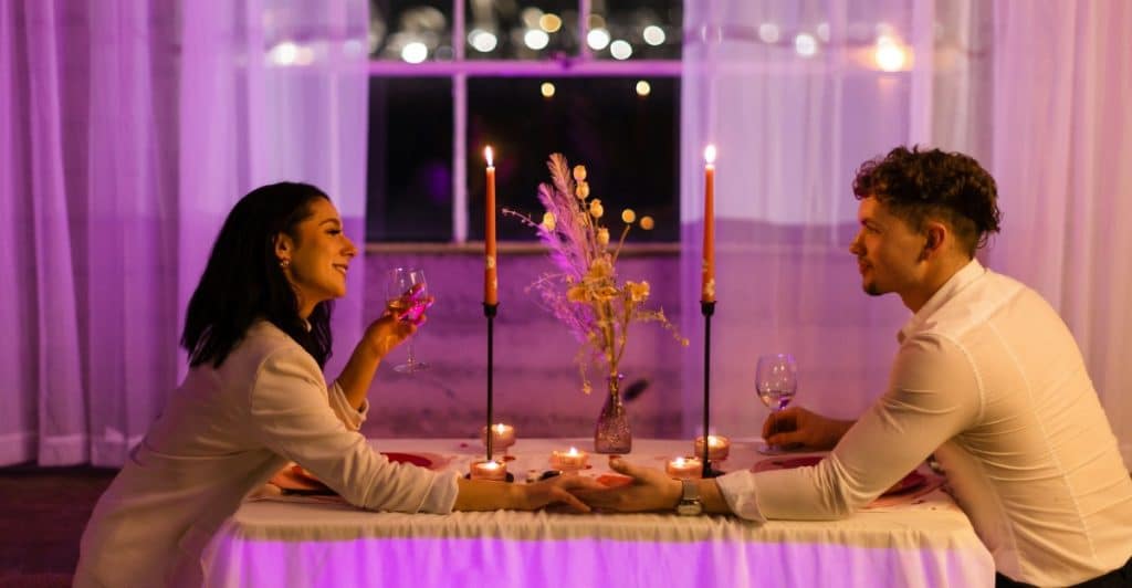 A couple having a candlelit dinner on a rooftop at night.