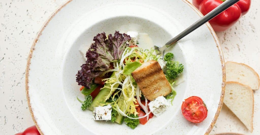 A plate of salad with fish and vegetables scattered around.