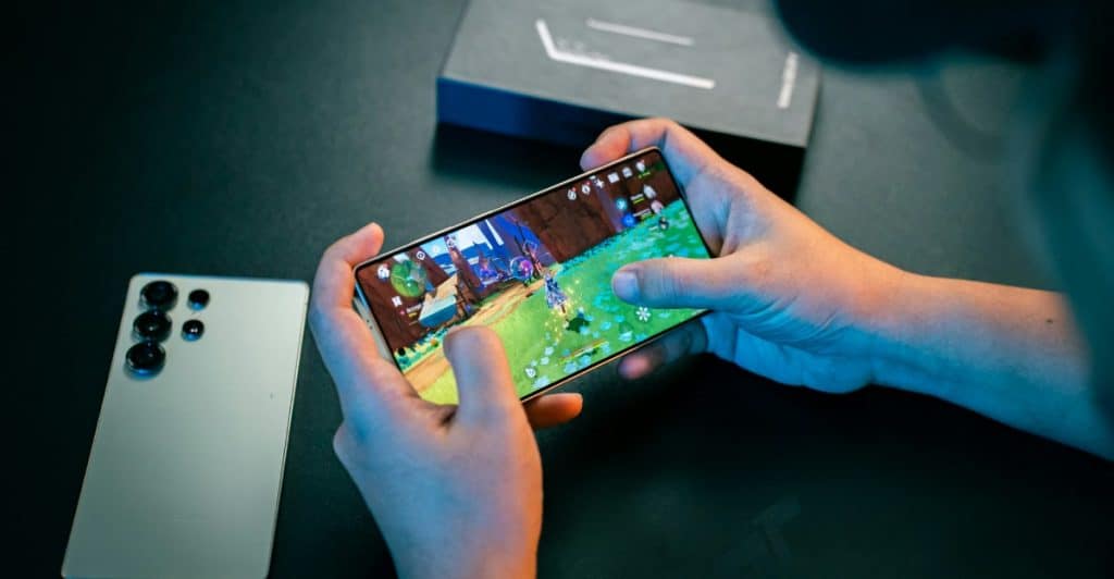 A person playing a video game on the Samsung Galaxy S25 Ultra, with another Samsung phone visible in the background.