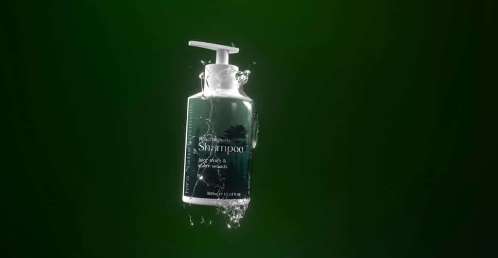 A bottle of shampoo with water droplets against a green background.