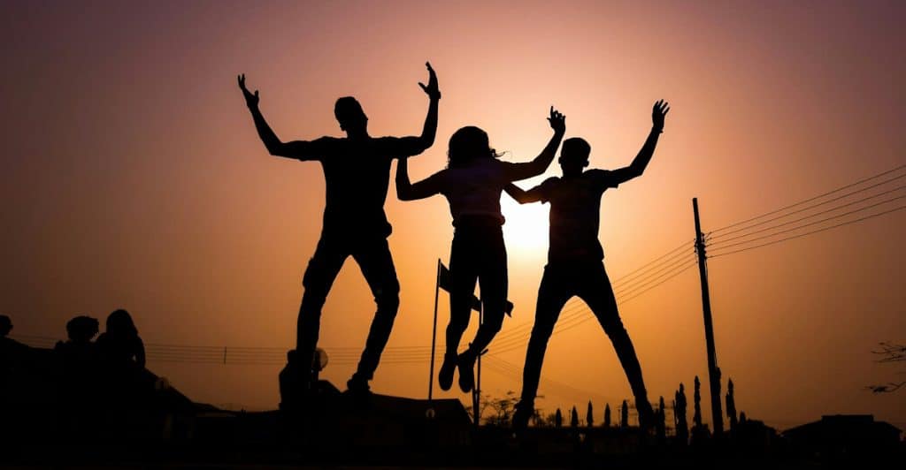 Silhouettes of three people jumping in the air against a sunset
