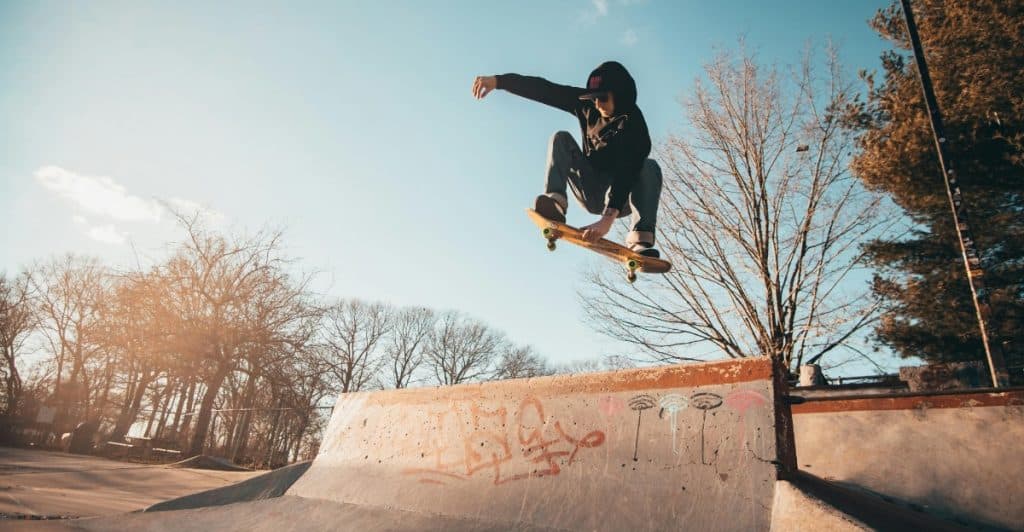 A person mid-air with arm extended on a skateboard at a skatepark.