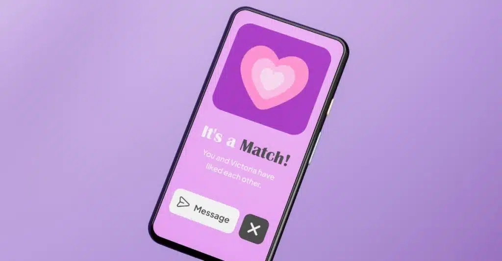 A smartphone screen displays a match notification with a large heart icon and the text "It's a Match!" on a purple background, surrounded by scattered red hearts.