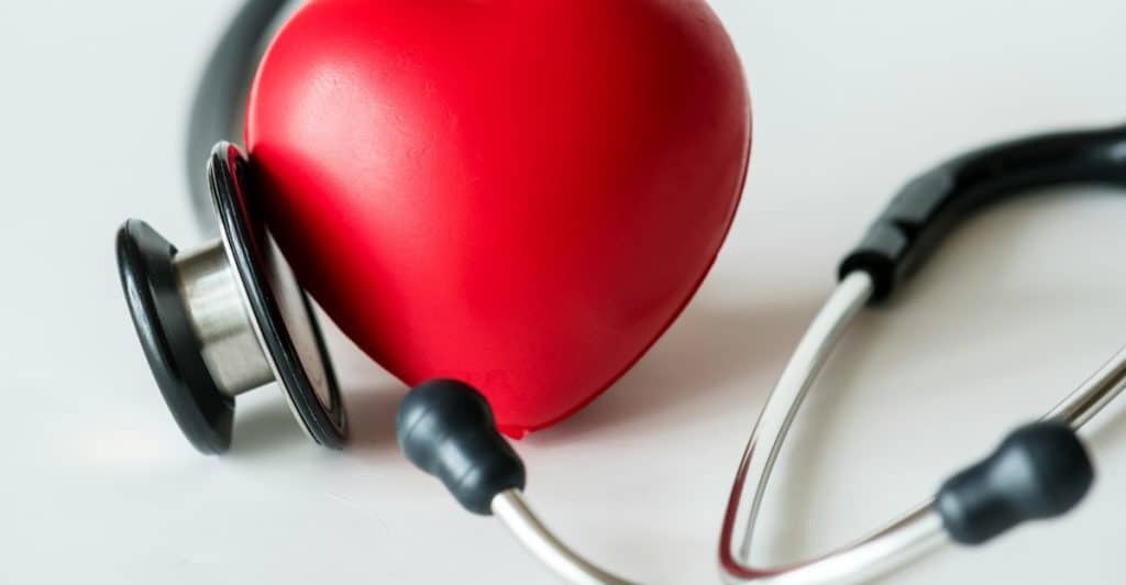 A stethoscope and a red heart-shaped object on a white surface.