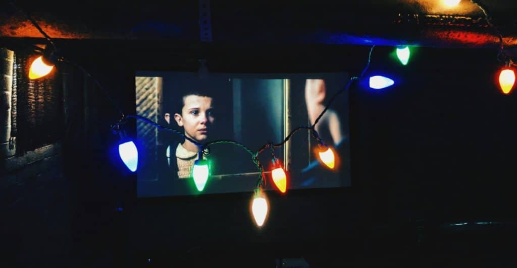 A scene from "Stranger Things" projected onto a screen with colorful lights.