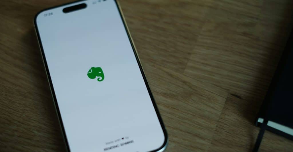 A smartphone displaying the Evernote app logo on a wooden surface.