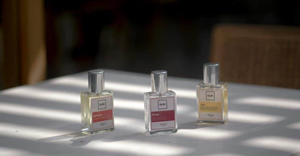 Three small bottles of fragrance lined up on a table.