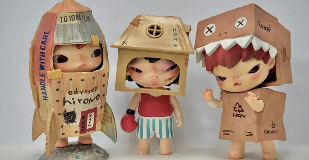  Three figurines with childlike faces, each wearing a different costume: a rocket, a house, and a dinosaur.