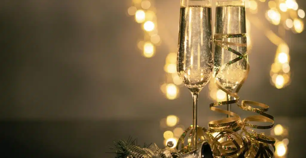 Two filled up wine glasses with blurred festive lights in the background.
