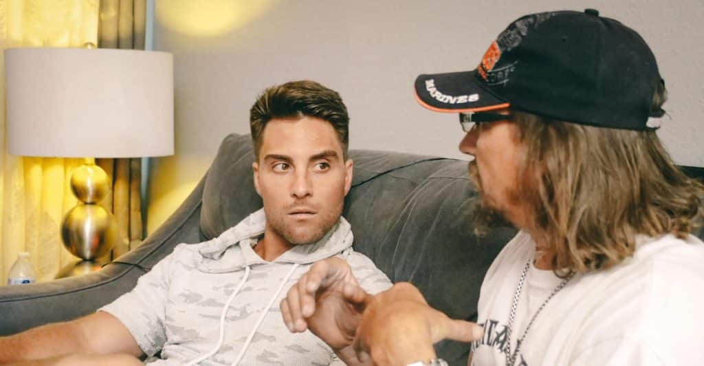 Two men having a conversation on a couch.