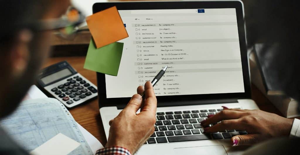 Two people looking at a laptop screen with documents and a calculator nearby.