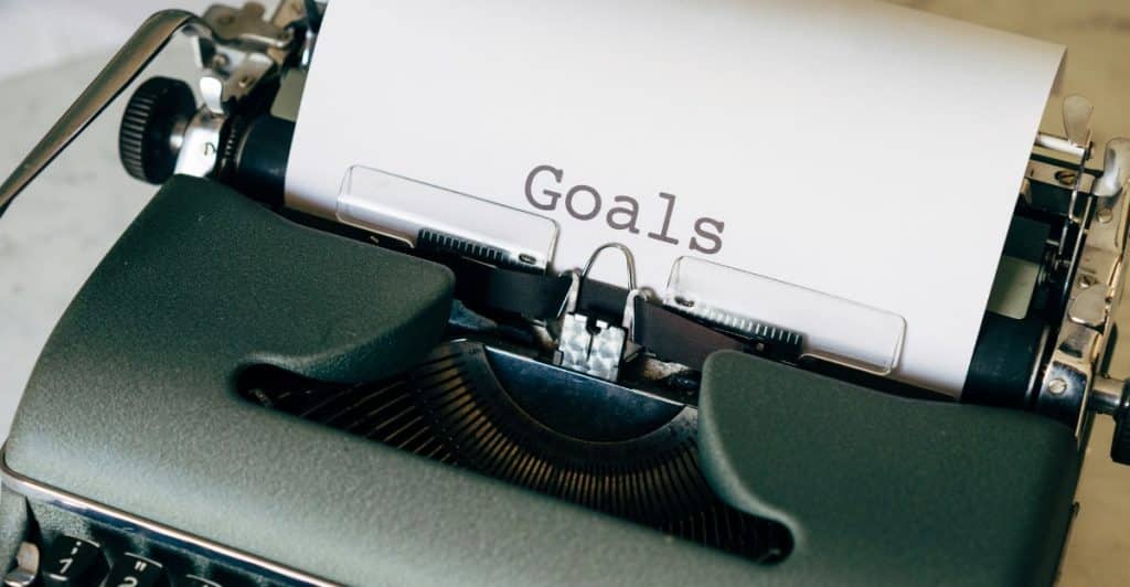 A vintage typewriter with a piece of paper inserted with the word "Goals" typed on it.