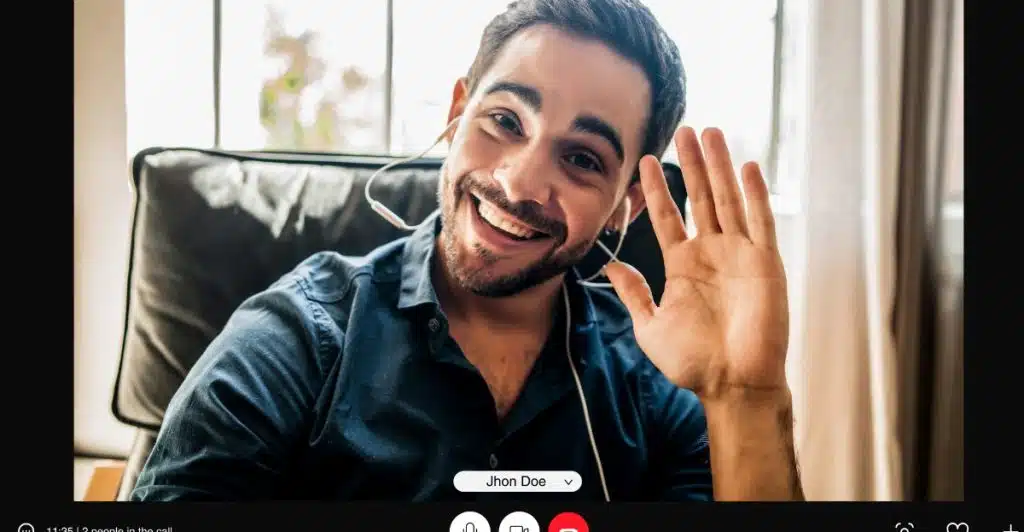 A video call interface with a man smiling and waving.