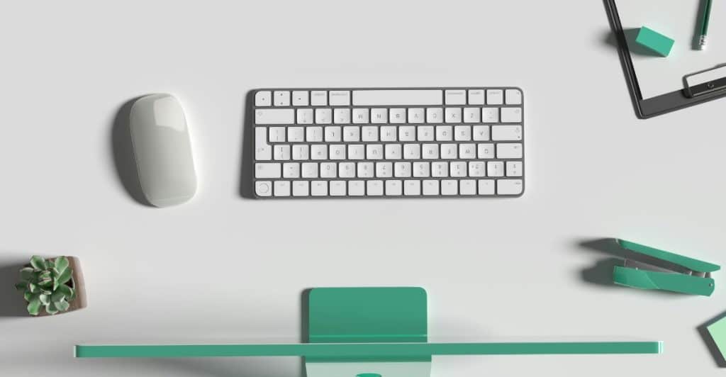 A white keyboard and mouse with green desk accessories on a light gray surface.