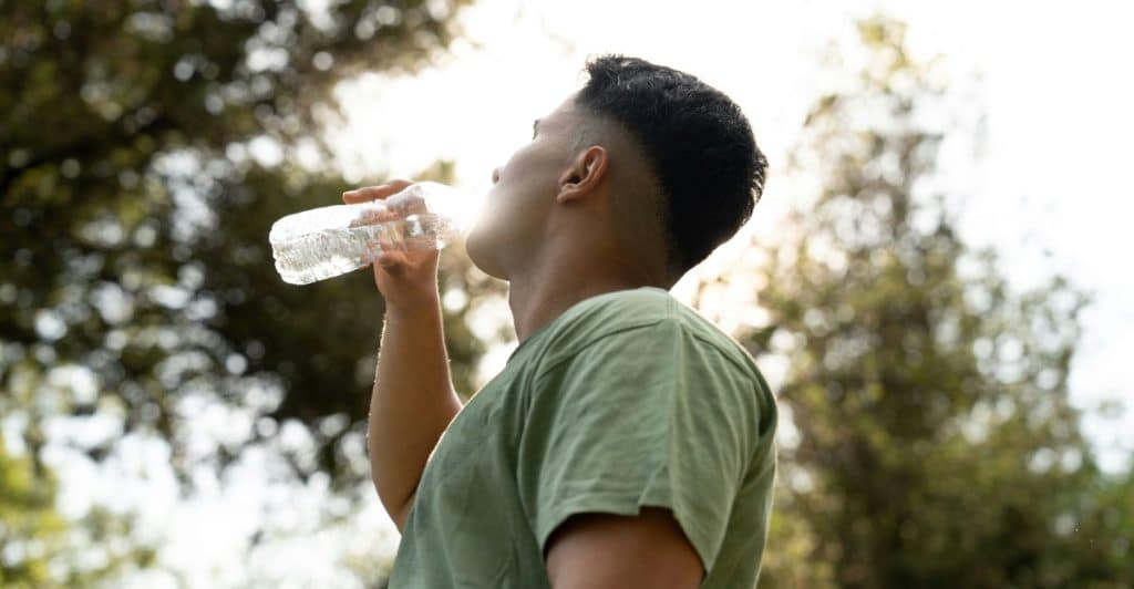 A man with a beard is sleeping on his side in a bed, covered by a white duvet.