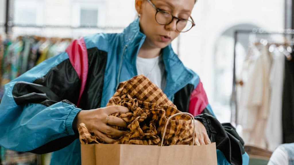 A woman putting a scarf in a bag.