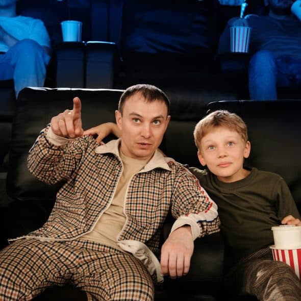 Father and son watching a movie in the cinema.