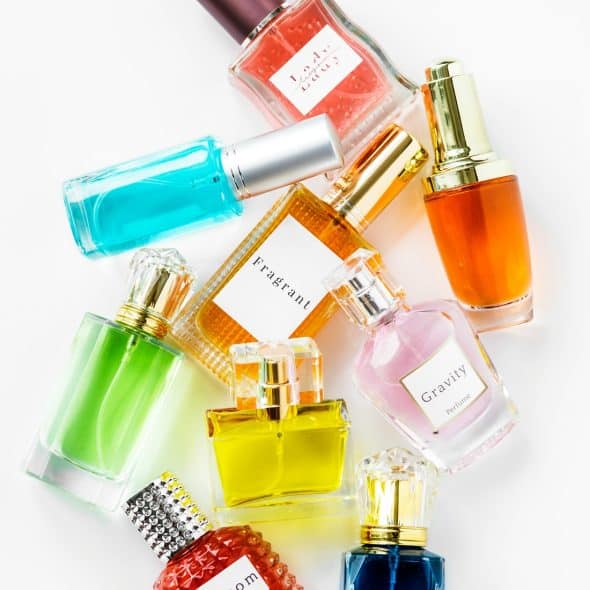 A top-down view of several fragrance bottles with different colored liquids and labels, scattered on a white surface.