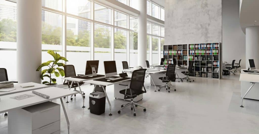 A well-lit office space with a large window letting in natural light, a desk with a computer monitor, and a comfortable chair, creating an inviting work environment.