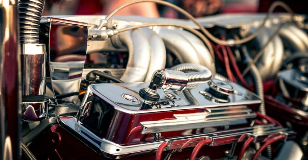 A close-up of a detailed and polished car engine with chrome and red accents.