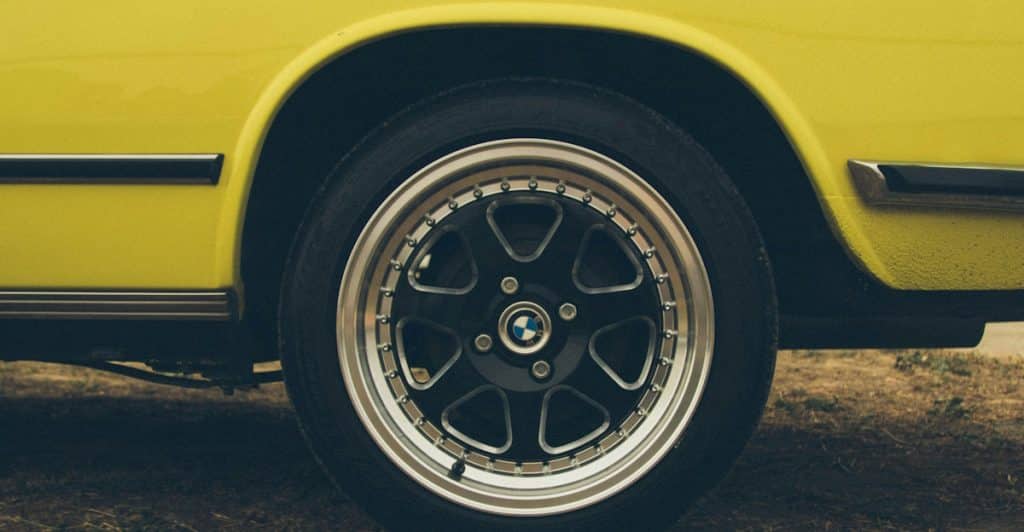 A close-up of a car's wheel and tire, with a yellow fender visible.