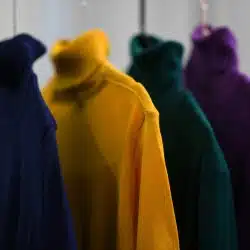 A close-up shot of several colorful turtleneck sweaters hanging on a clothing rack.