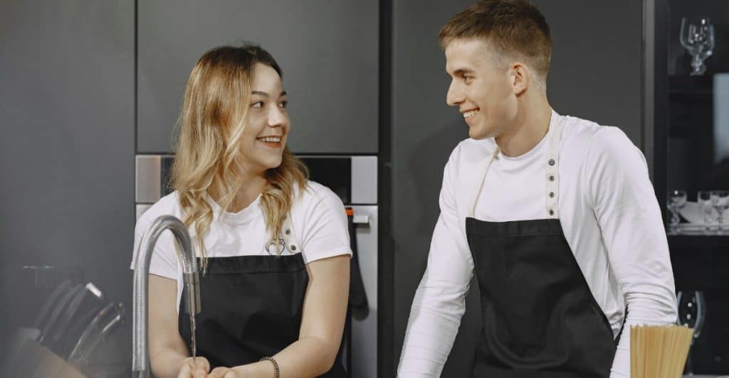 A couple cooking together in a kitchen.