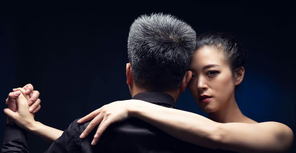 A man and a woman dancing together with their arms intertwined.