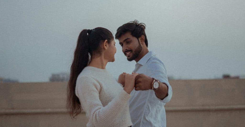 A man and a woman holding hands and looking into each other's eyes.