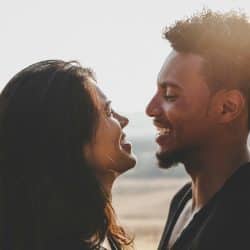 A man and woman laughing with each other, bathed in sunlight outdoors.