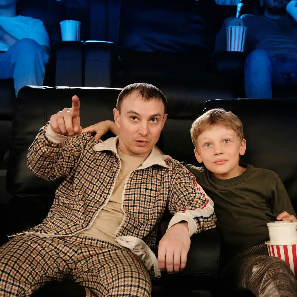 Father and son watching a movie in the cinema.