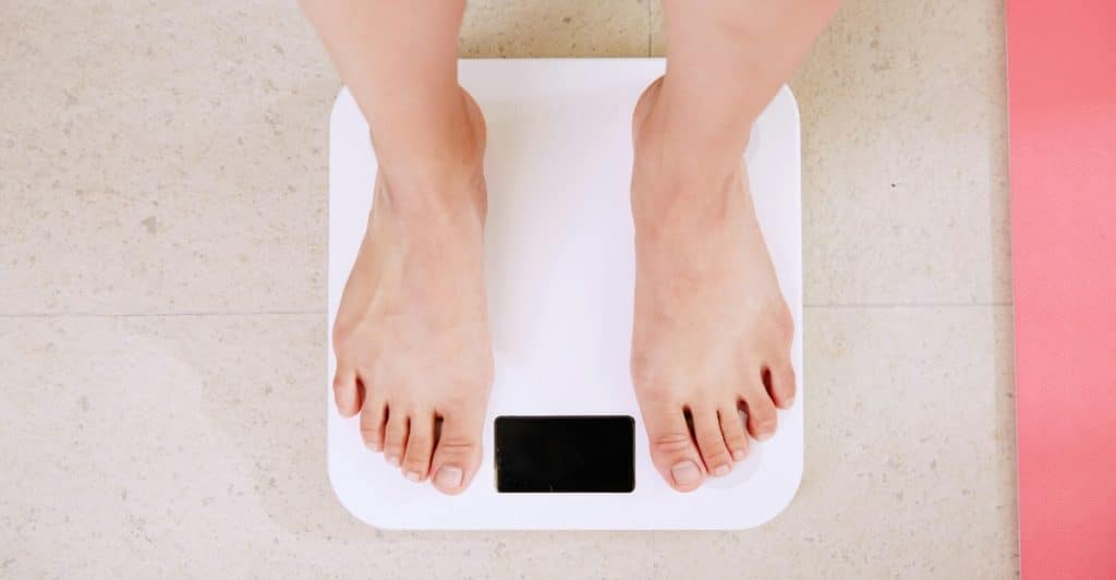 A person's feet on a white digital bathroom scale.