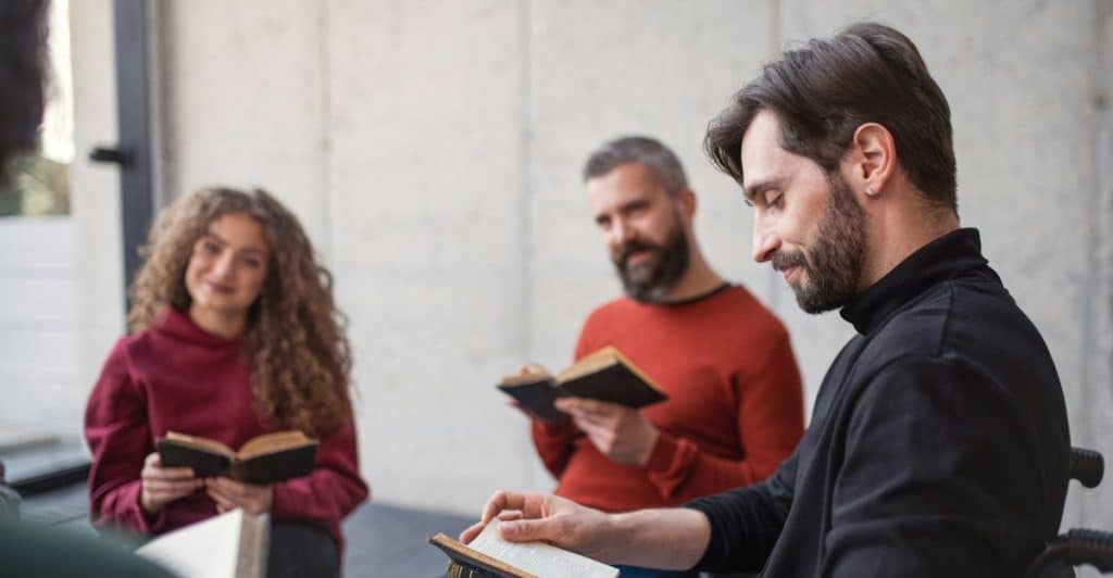 A group of people sitting together and reading books, engaged in a relaxed discussion or study session.